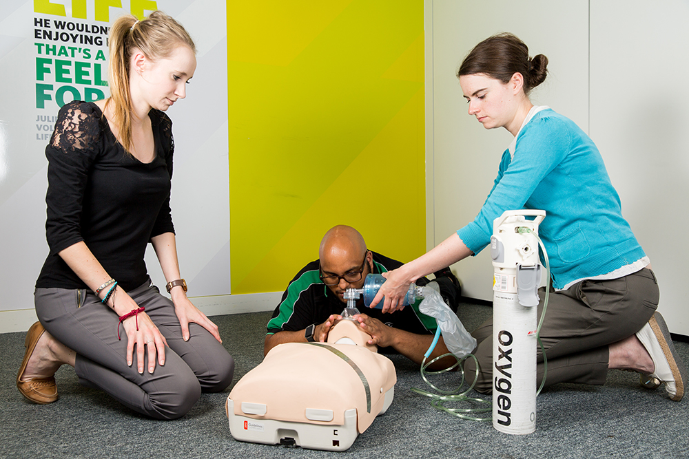 Course students practise application of medical gas to manikin, supported by St John Ambulance trainer