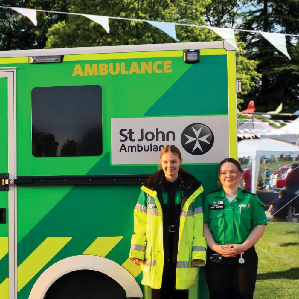 Two cadets standing beside an SJA ambulance