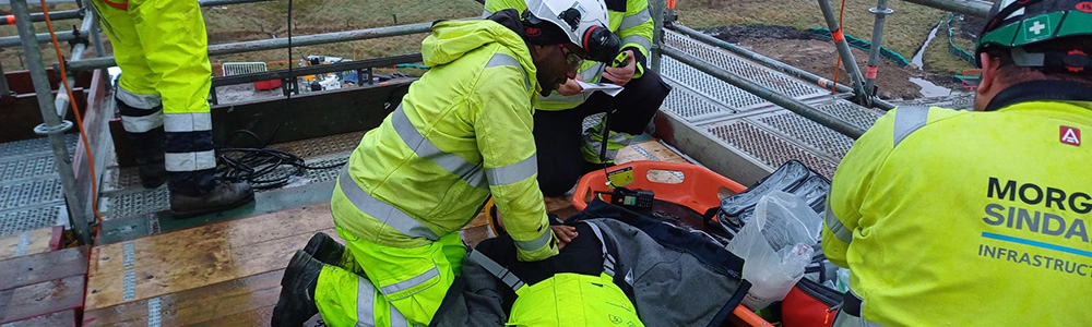 A construction worker performing CPR on his colleague.