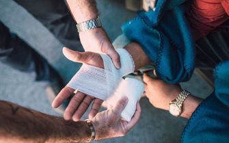 A person applying a bandage to a casualty's hand. A person applying a bandage to a casualty's hand.