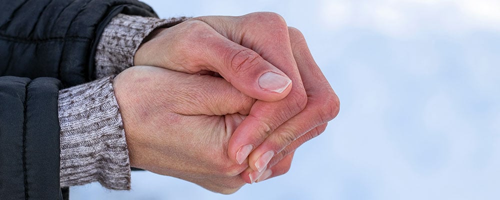 A person rubbing their hands together for warmth.