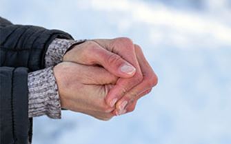 A person rubbing their hands together for warmth.