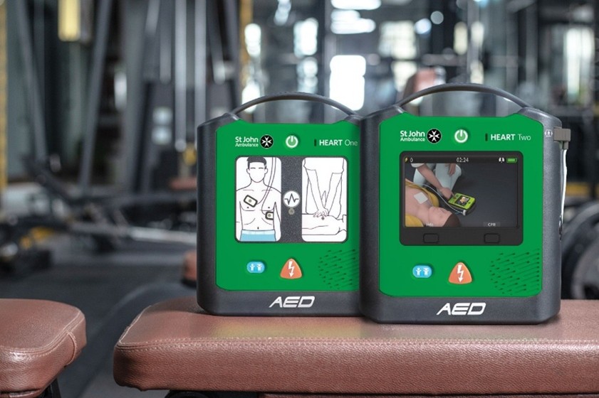 The HEART One and HEART Two defribrillators on a table, inside a gym.