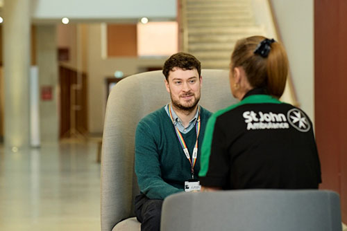 A man speaking with a St John Ambulance Trainer.