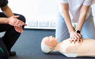 A woman taking instructions from a St John Ambulance trainer about chest compressions. A woman taking instructions from a St John Ambulance trainer about chest compressions.