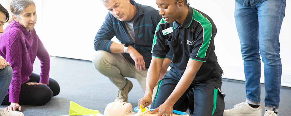 A St John Ambulance trainer demonstrating first aid skills to a group of learners.