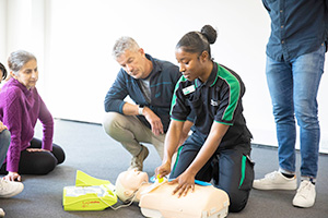 A St John Ambulance trainer demonstrating first aid skills to a group of learners.