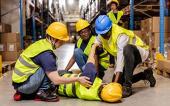 A warehouse worker collapsed on the floor, while his colleagues tend to him. A warehouse worker collapsed on the floor, while his colleagues tend to him.