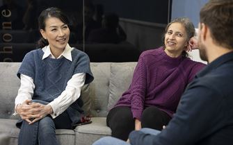A group of people sitting on a couch and chatting.
