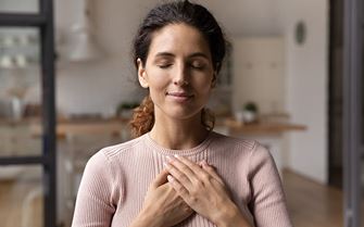 A woman with her hands against her chest, smiling.