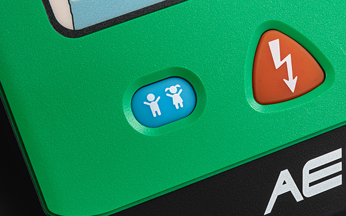 A close-up of one of the HEART defibrillators, showing the adult/child mode button.