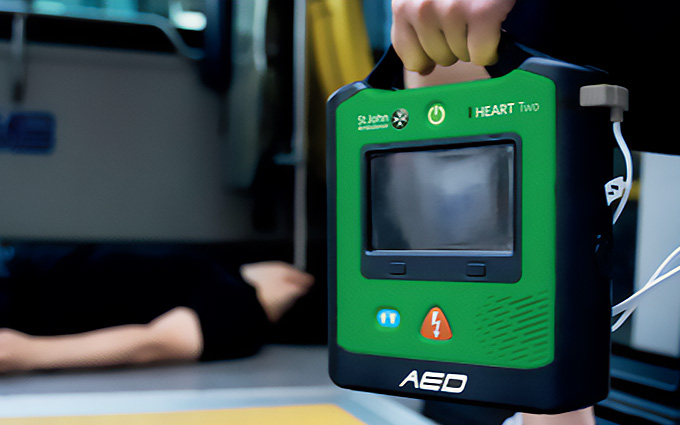 A rescuer carrying a HEART defibrillator in an emergency scene.