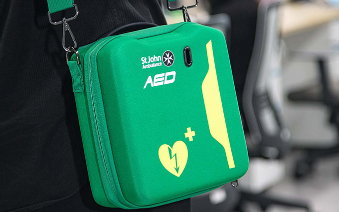 A person carrying a HEART defibrillator inside of a carry case.