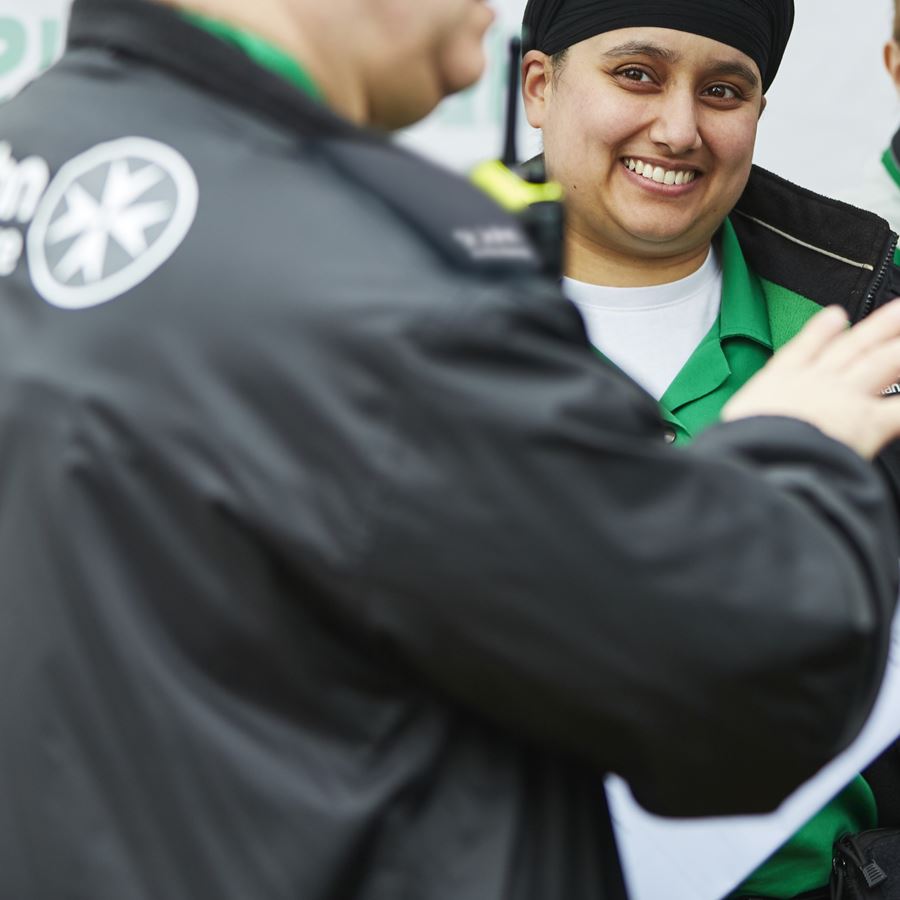 A volunteer standing and smiling at a man talking.