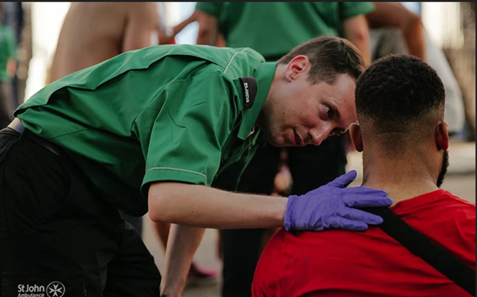 A volunteer putting their hand on the shoulder of a man sitting down.