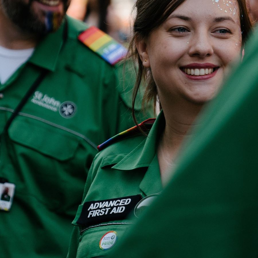 The face of an Advanced First Aid volunteer with glitter on their face, looking to the side, smiling.