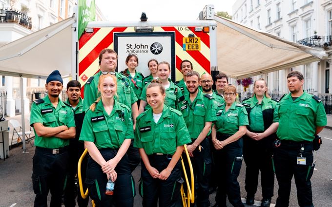 Large group of smiling volunteers standing in front of an ambulance. Large group of smiling volunteers standing in front of an ambulance.