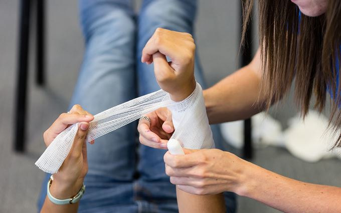 Someone applying an arm bandage