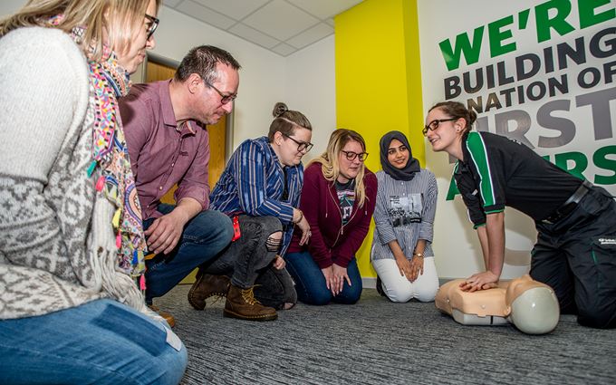 St John Ambulance first aid trainer teaching CPR to a group