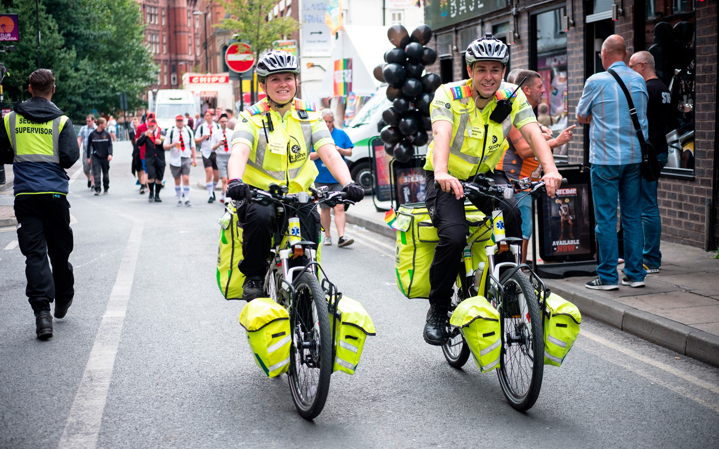 two-emergency-cycle-responders-cycling-down-street-during-festival-large-pod.jpg