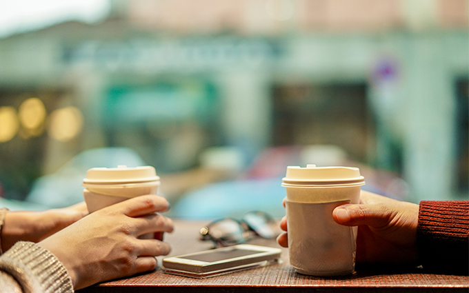 Two people with hot drinks sitting at a table