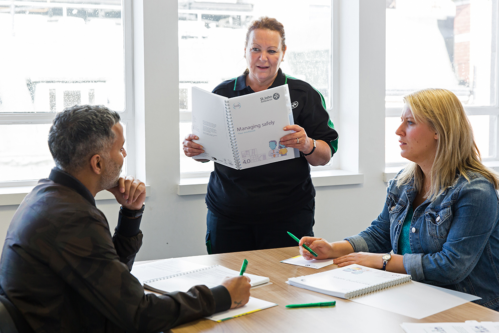 St John Ambulance trainer supports course attendees through workbook exercises