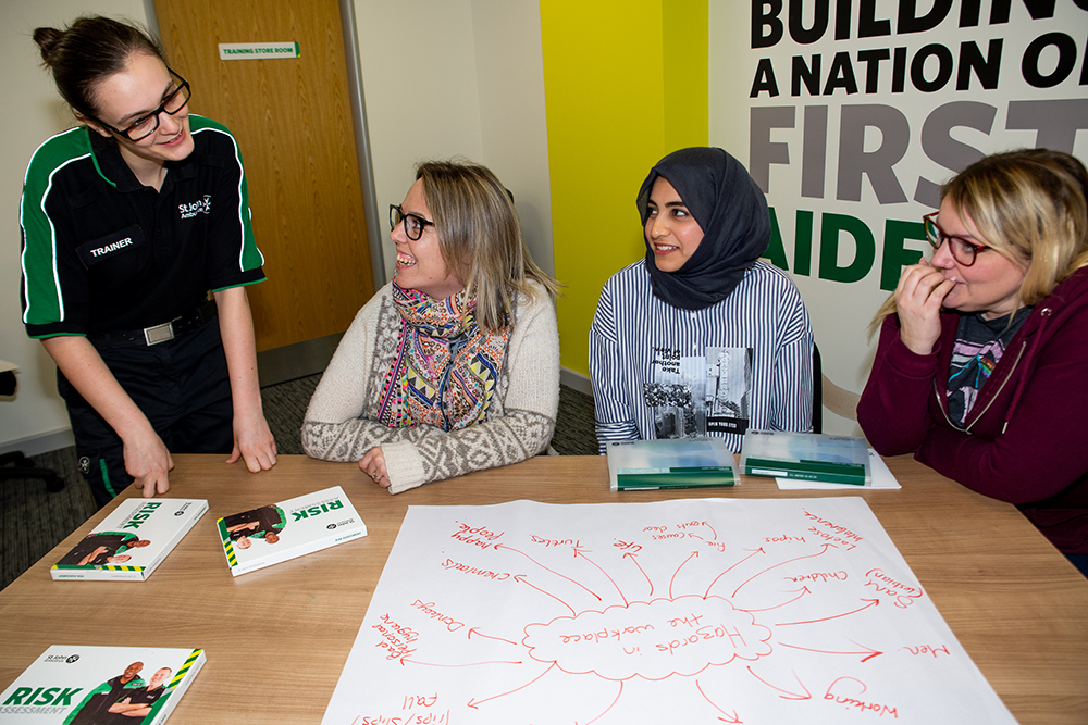 Course attendees work together in group exercise to identify hazards in the workplace, wiht support from a St John Ambulance trainer