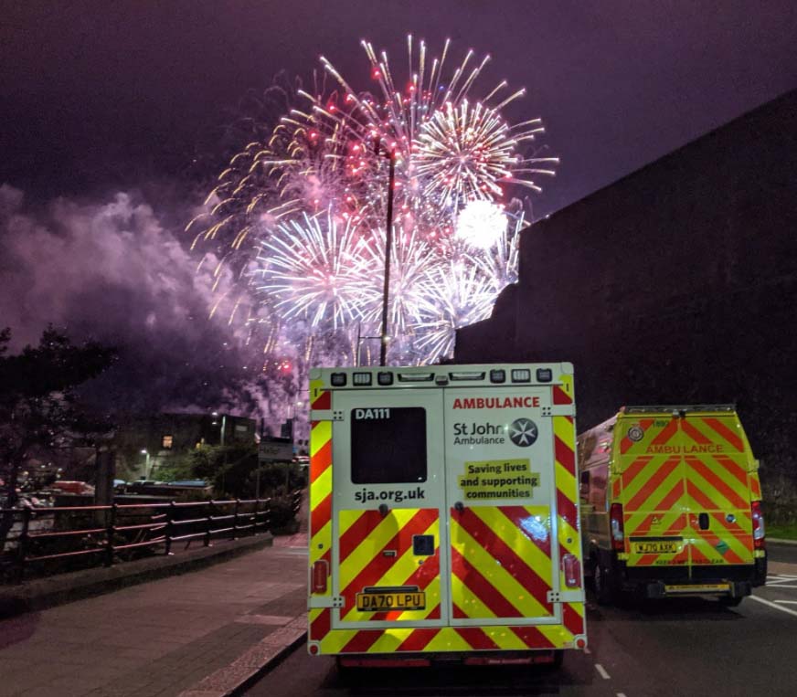 Two St John Ambulance ambulances with a firework display in the background