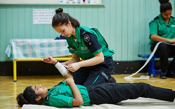 2 cadets practising bandaging an arm.  2 cadets practising bandaging an arm.