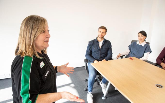 A first aid trainer speaking to a class of first aid students