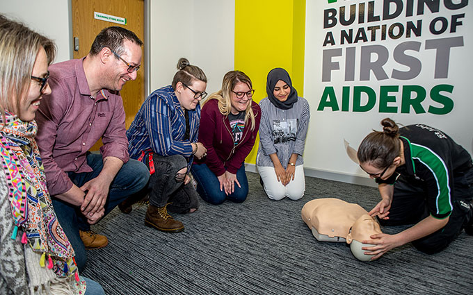 Trainer teaches CPR by lifting a training mannequin chin to check if the airway is open in a first aid training course. 