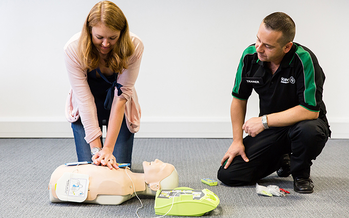 St John Ambulance class participant practicing CPR using a training mannequin.