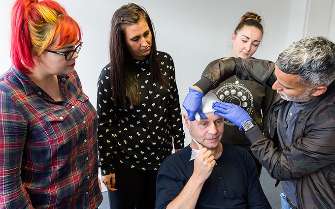 First aid course participants applying a head bandage First aid course participants applying a head bandage