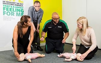 First aid course participants practicing baby CPR on a training mannequin