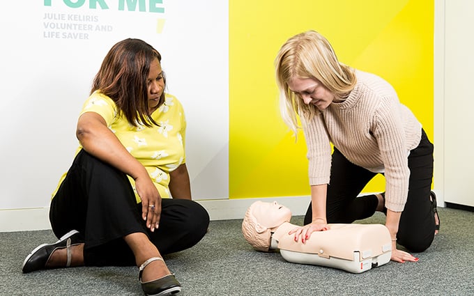 First aid class participants practicing child CPR using a training manikin.