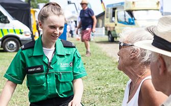 First aider attending elderly couple at outdoor event First aider attending elderly couple at outdoor event